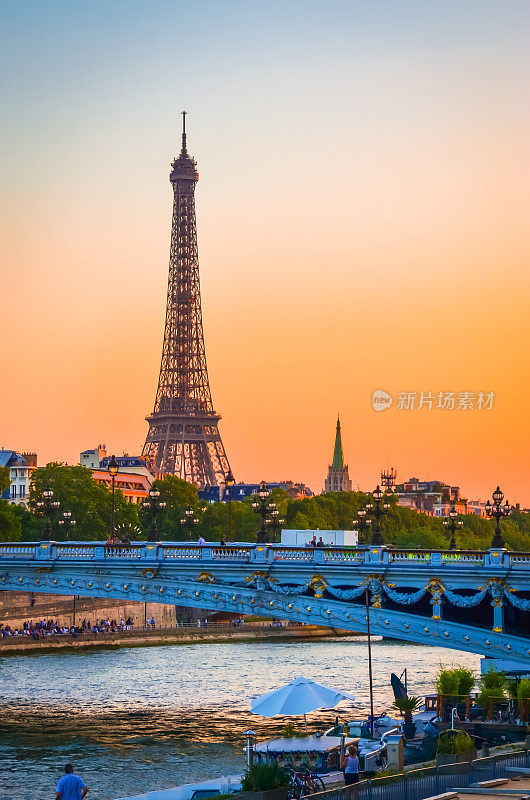 法国巴黎的埃菲尔铁塔、亚历山大三世大桥和塞纳河的日落景观。