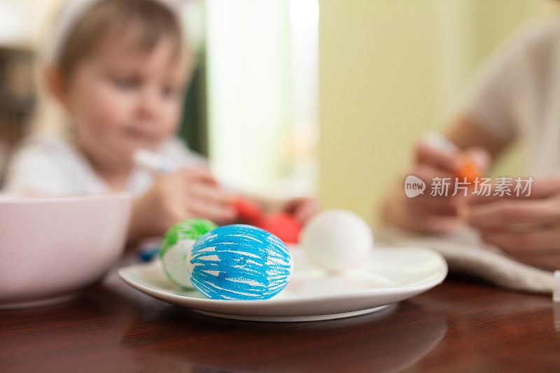 妈妈和孩子在为复活节画彩蛋。妈妈和蹒跚学步的男孩庆祝复活节