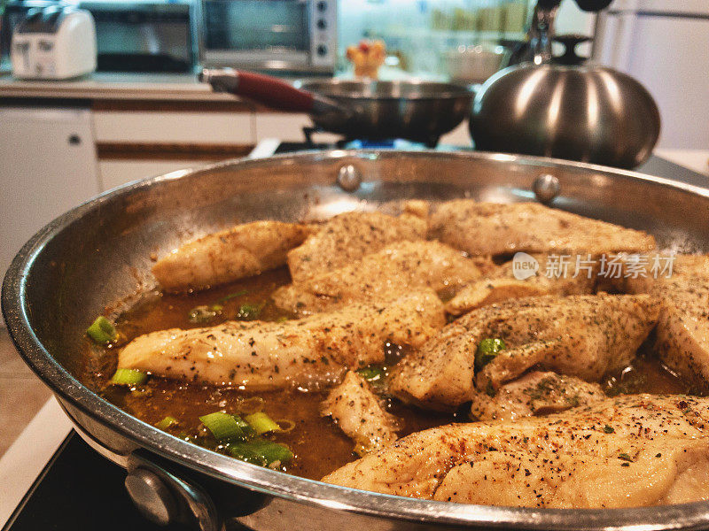 烹饪柠檬鸡类食物，在煤气炉上用不锈钢平底锅烹饪