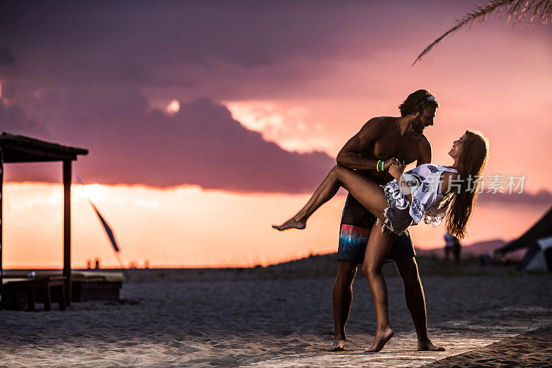 日落时分，浪漫的情侣在沙滩上跳舞。
