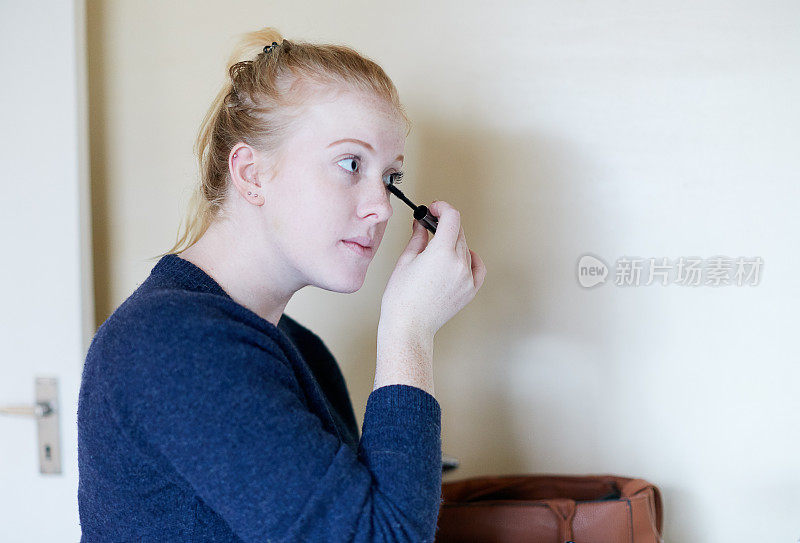 年轻的金发女人正在涂睫毛膏