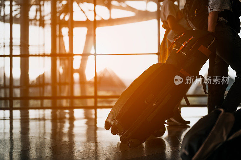 一家人带着行李在机场散步的剪影。行李在机场候机楼。