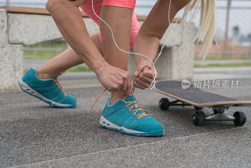 近距离的运动女人系鞋带，而跪在户外