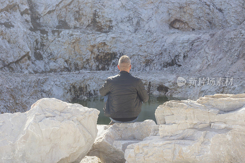 成年游客坐在废弃的大理石采石场