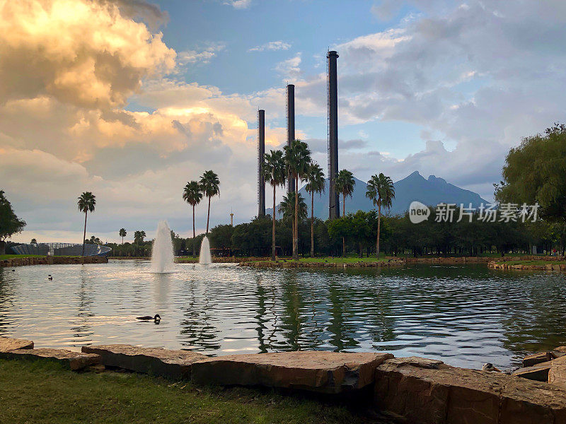 蒙特雷Fundidora公园的日落，可以看到湖泊、喷泉、鸭子和工厂的烟囱
