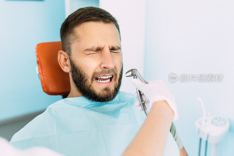一个人在牙医那里治疗他的牙齿。牙科医生检查牙齿。牙科保健。一个男人害怕治疗他的牙齿。害怕治疗牙齿。在牙科诊所拔牙。本空间