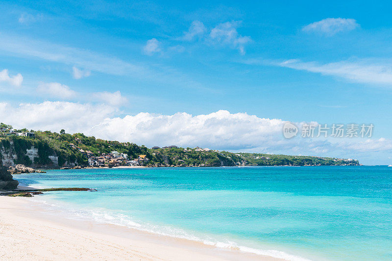 巴厘岛的海滩景象-碧绿的印度洋，白色的沙子和蓝色的天空在背景。