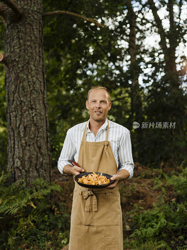 男男厨师在户外用鸡油菌和煎锅