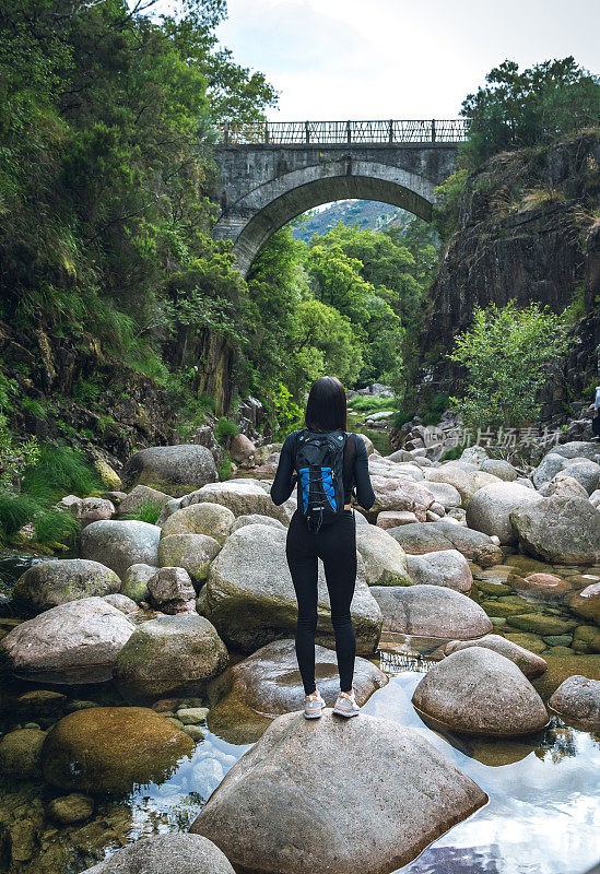 背着背包的年轻女子徒步旅行者在户外的山区旅行