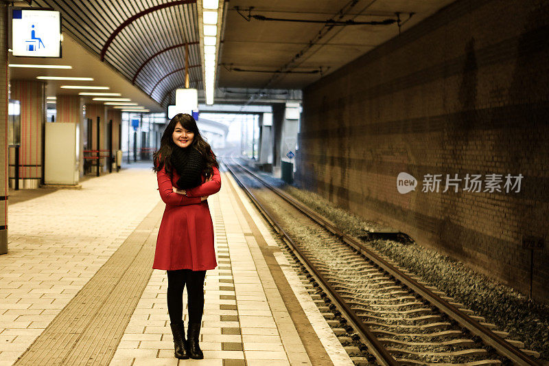 年轻女子微笑着在站台等地铁