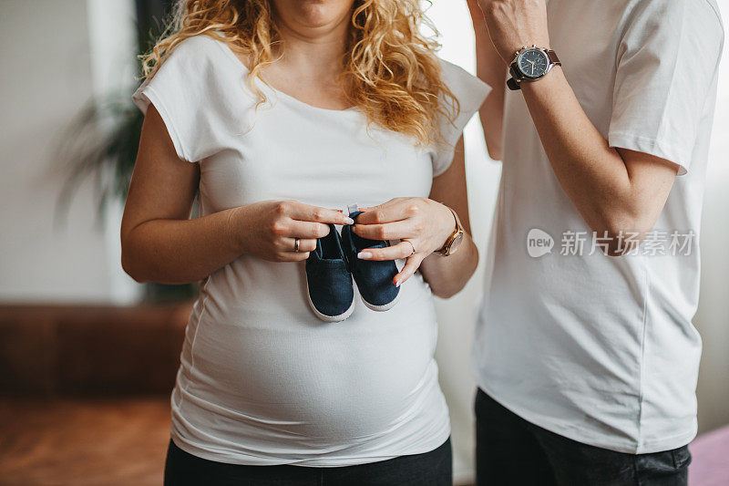 一对抱着婴儿鞋的怀孕夫妇