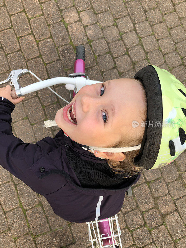 戴着头盔的5岁女孩。孩子正在骑自行车。前视图。
