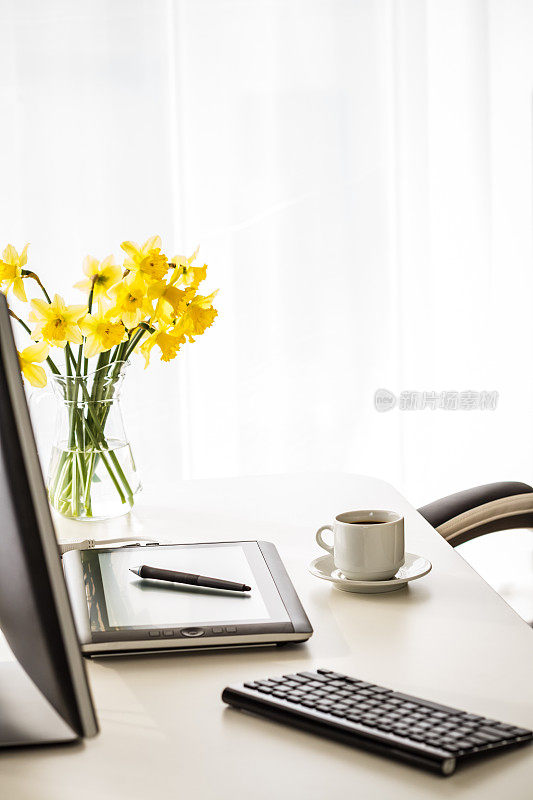 一张摆放在办公桌上的彩色的黄色水仙花