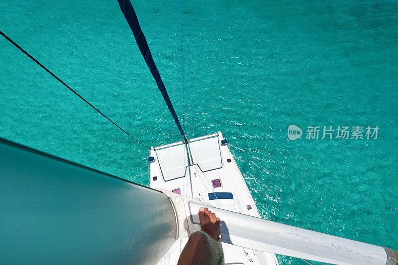 在双体船桅杆上的人向下看热带水域