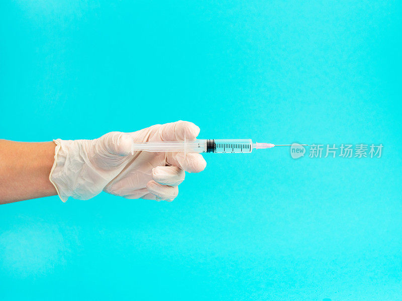医生手持注射疫苗的医用注射器，在蓝色背景上注射