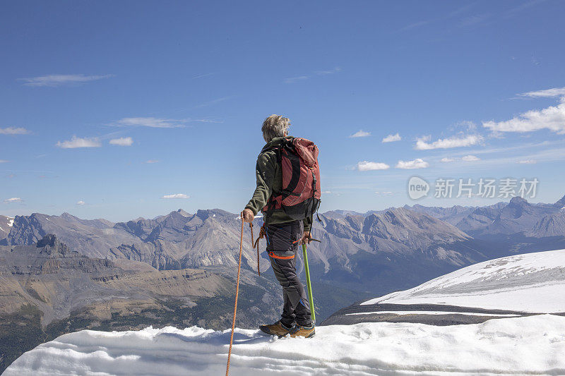 一位男性登山运动员到达了雪山的顶峰