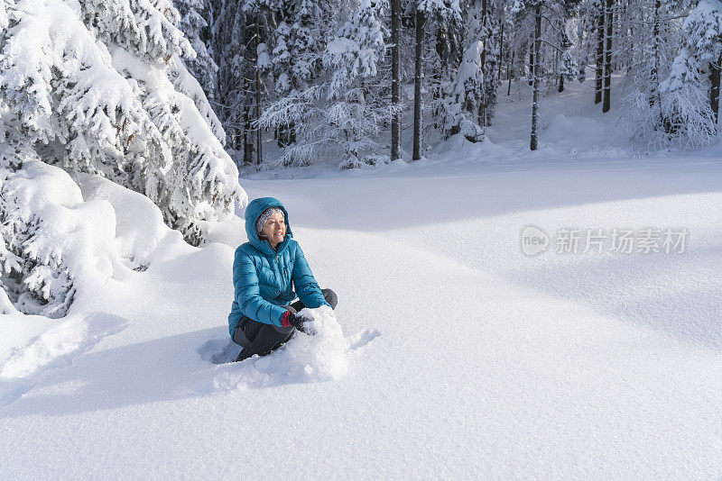 在冬天的森林里，成熟的女人穿着皮大衣向空中抛雪