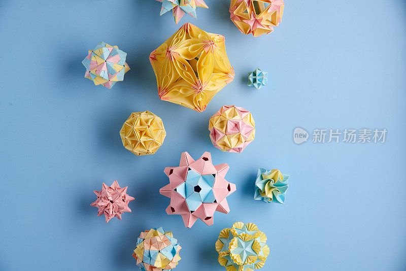 Set的multicolorÂ手工制作modularÂ折纸球或Kusudama孤立在蓝色背景。视觉艺术，几何学，折纸艺术，纸工艺品。俯视图，特写，选择性聚焦，复制空间。