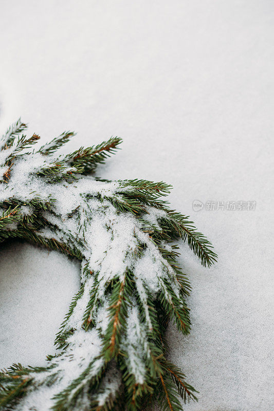 由天然冷杉树枝制成的白雪覆盖的圣诞花环