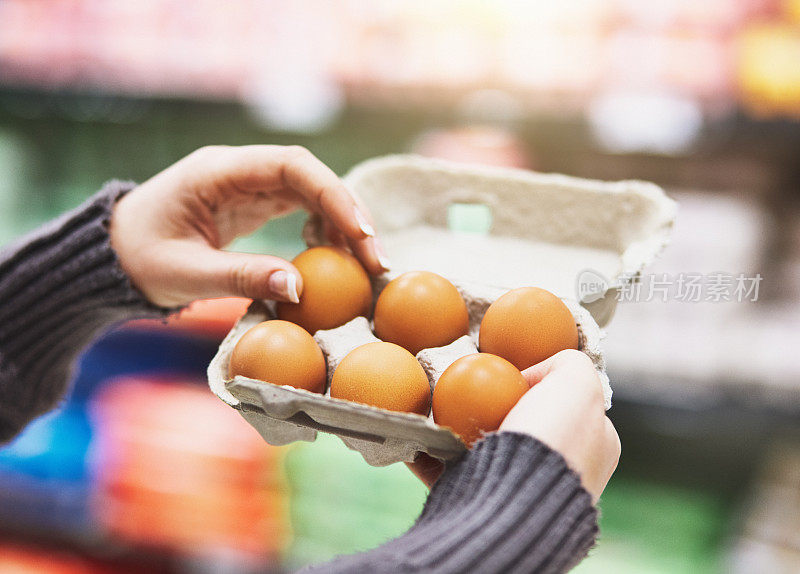 一位妇女在超市里从一盒鸡蛋中取出半打鸡蛋