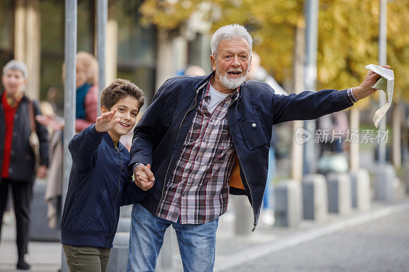 一个年长的男人和小男孩的肖像谁是站在城市的街道和试图赶上一程。