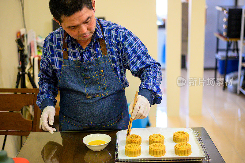 面包师在烤盘上用鸡蛋面团画自制月饼