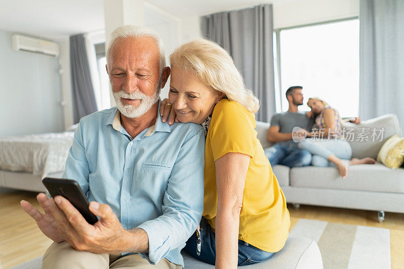 快乐的老人在家里和家人一起放松的时候使用电话。