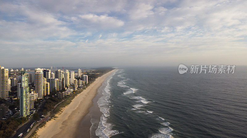 冲浪者在清晨的天堂海滩和高楼大厦。黄金海岸,澳大利亚,