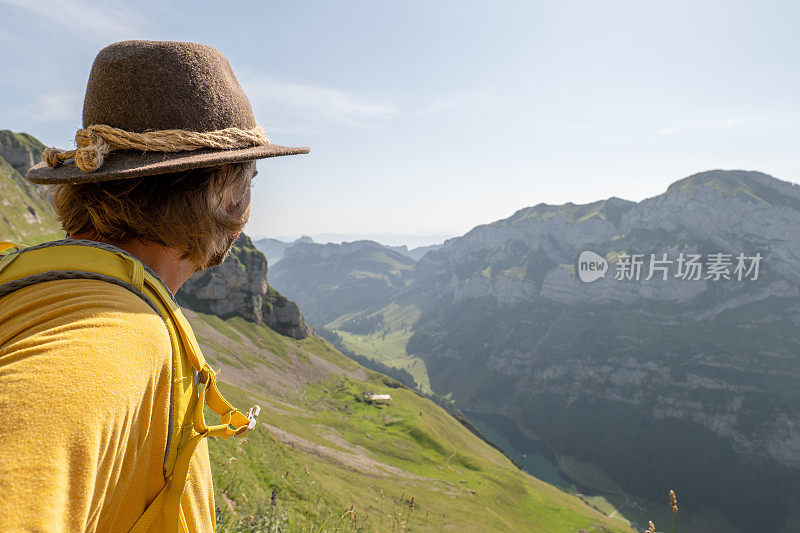 侧视图-年轻男子在瑞士阿尔卑斯山徒步旅行，背景是美丽的山峰