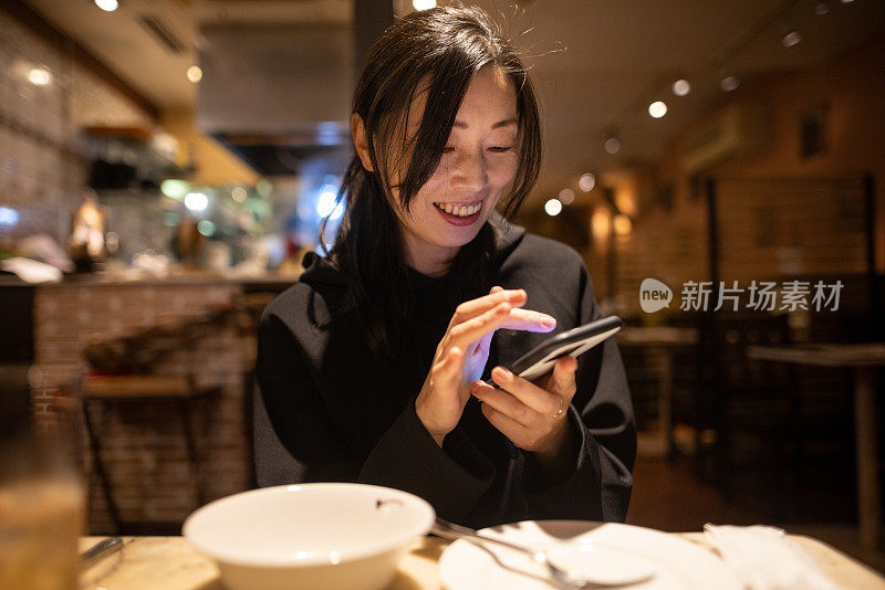 在餐厅用智能手机的女人