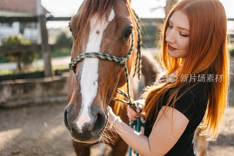 一个红头发的女人抚摸着一匹马