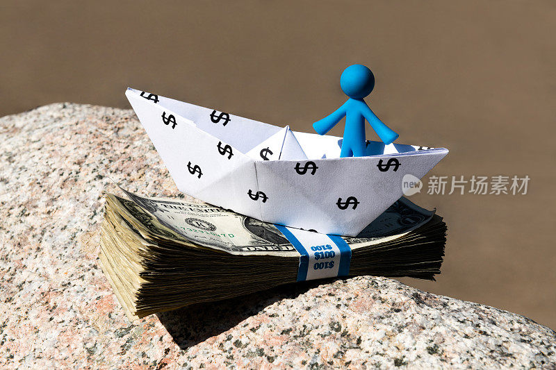 一个有美元符号的纸船，一个人形雕像和一叠美国钞票