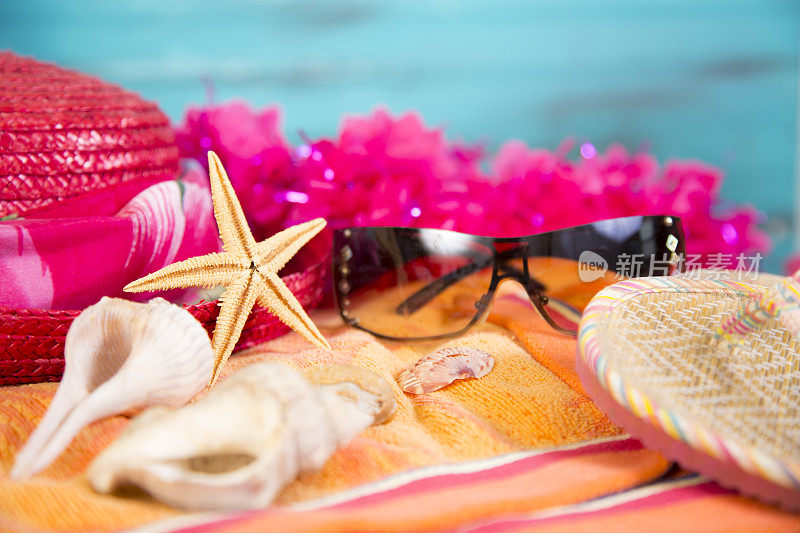 暑假。沙滩毛巾与绿松石水看背景。大型海星和其他贝壳。太阳镜和花环。