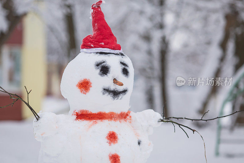 雪人戴着圣诞帽，背景是冬天的雪。寒冷的天气。霜