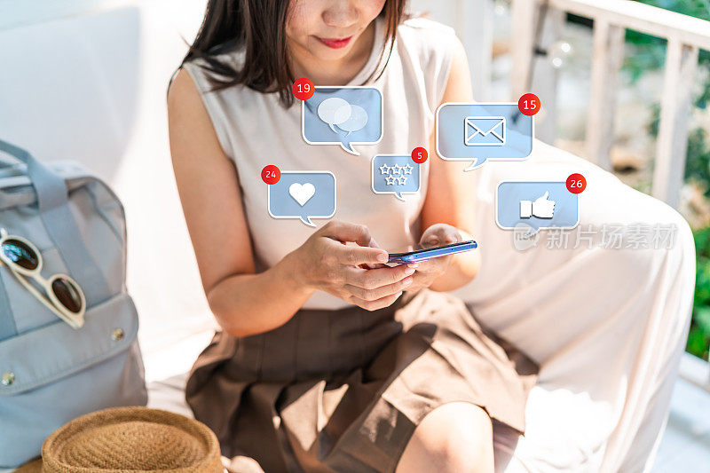 年轻女子在暑假旅行时使用带有社交媒体互动和通知图标的手机