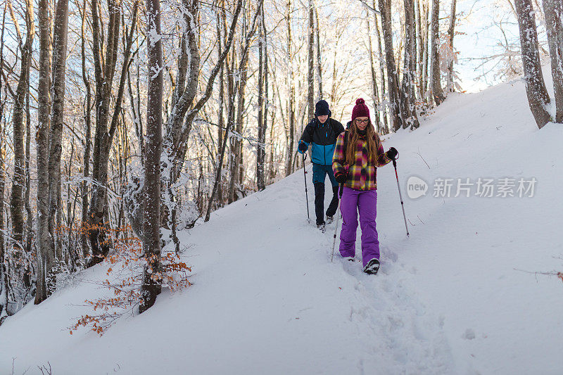 两个年轻的徒步旅行者正从雪山小径上爬下来