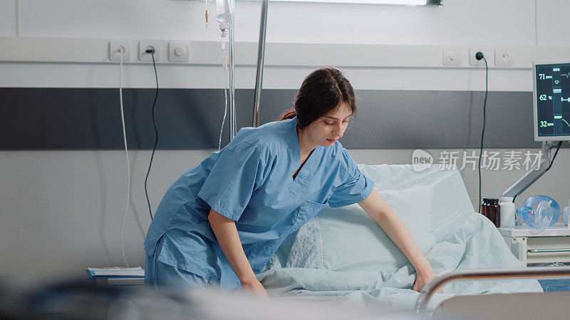 在医院病房里做护士准备床位的妇女