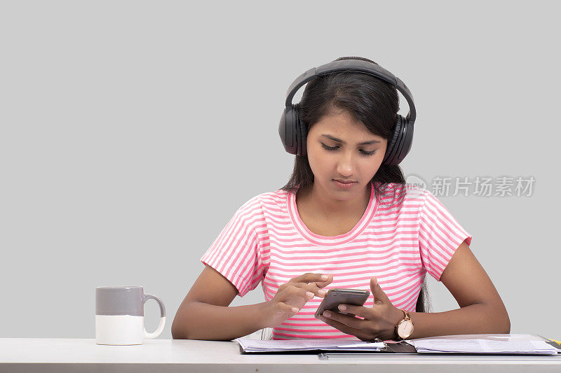 年轻女子一边工作一边戴着耳机听音乐的照片
