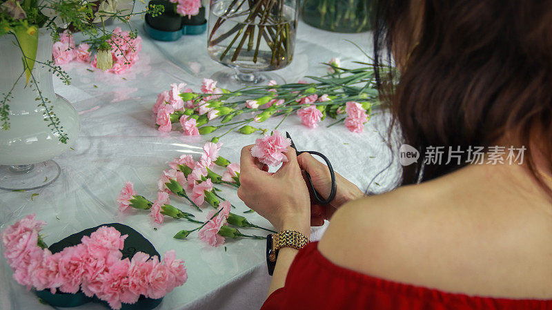 一位亚洲妇女正在上插花课，她用许多康乃馨做了一束心形的花，送给母亲庆祝母亲节。