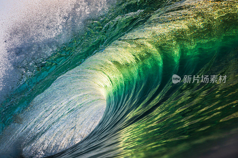 近景，翠绿的波浪在金色的光线下冲破海洋