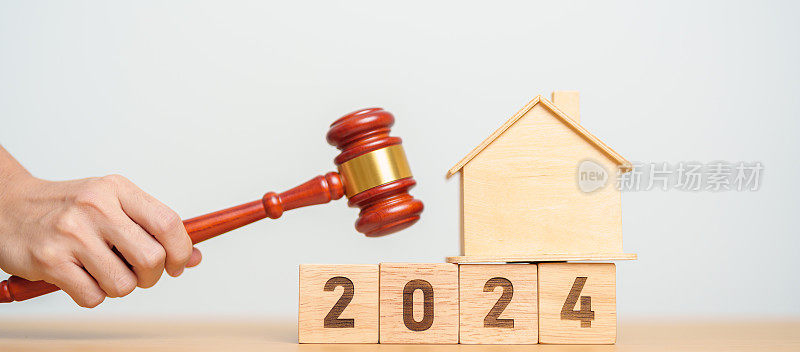 不动产法，房屋保险，房产税，拍卖和投标概念。法院的桌子上放着2024年的小玩具屋模型和小木槌。