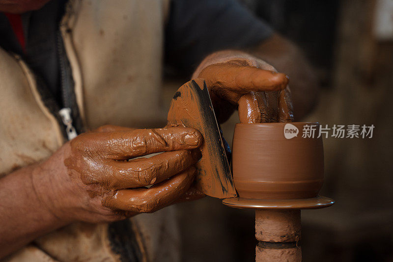 一位老人正在制作一个陶杯