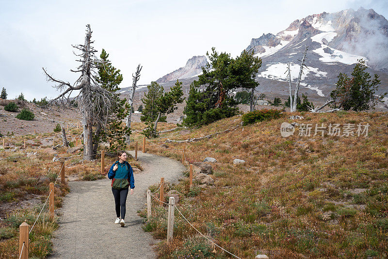 背包客妇女徒步旅行在雷尼尔山前的道路上覆盖着雪在美国华盛顿州冬天