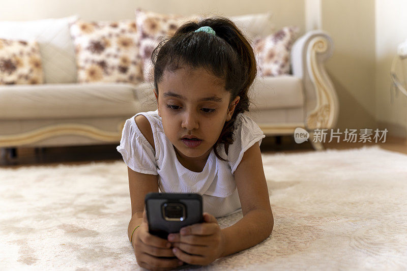 女孩在家里使用智能手机。