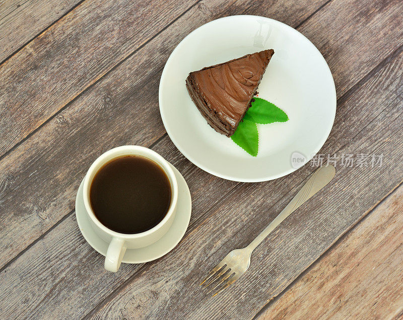木桌上摆着一盘薄荷巧克力海绵蛋糕和一杯热黑咖啡。