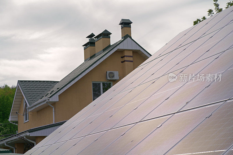 私人住宅屋顶上的太阳能电池板。配有太阳能板的大型家庭住宅。砖砌的两层楼的房子提供了太阳能发电，以满足自己的需要