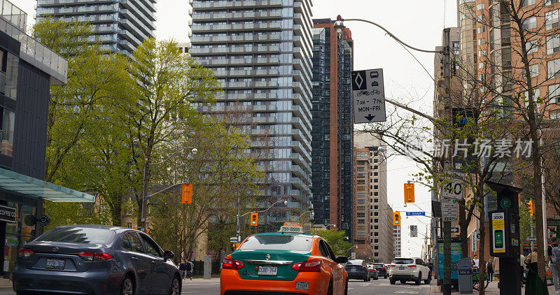 加拿大多伦多——2023年5月6日:多伦多每日忙碌。橙色出租车在繁忙的街道上穿梭，现代摩天大楼高耸入云的城市景观，真正的北美城市生活。