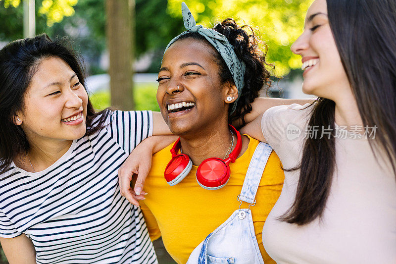 三位团结的多民族女性朋友在户外一起欢笑