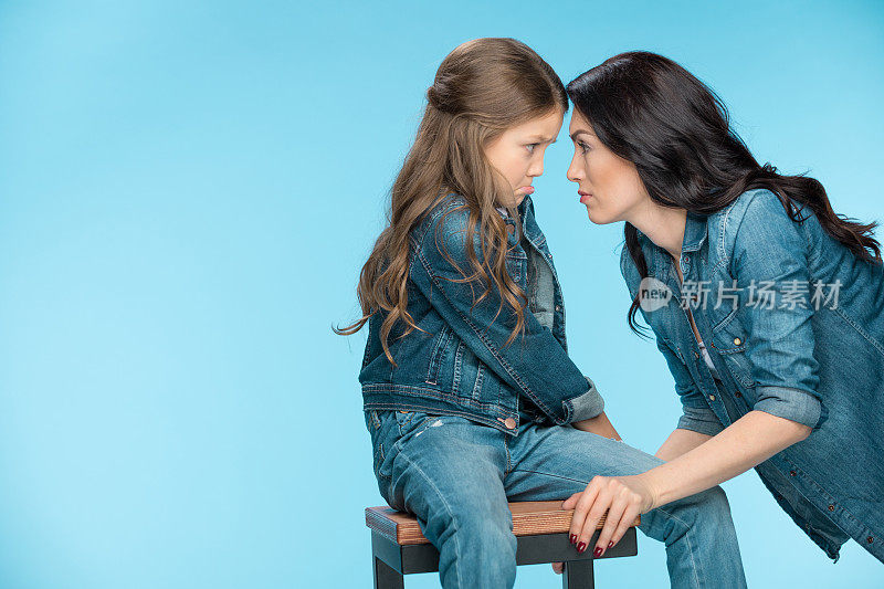 生气的女儿和母亲看着对方在工作室的蓝色