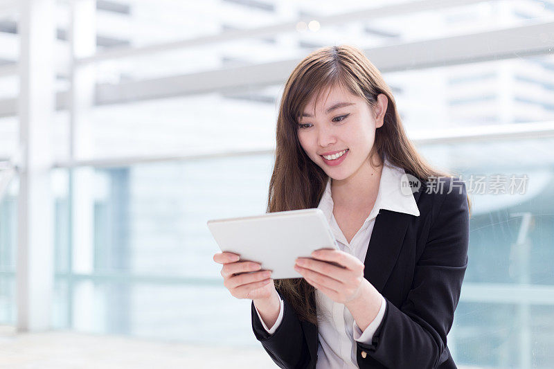 亚洲成功女商人在办公室走廊使用平板电脑